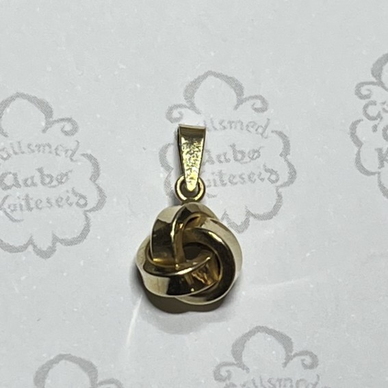 Gold interwoven knot pendant on a light background, hanging from a small loop.